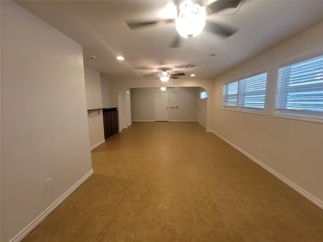 an empty room with a chandelier fan and windows