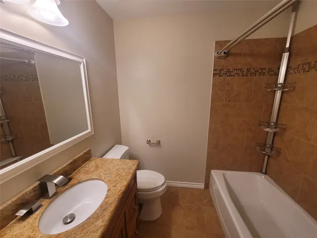 a bathroom with a granite countertop bathtub shower sink vanity and toilet