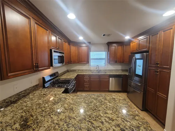a large kitchen with stainless steel appliances granite countertop a stove refrigerator and microwave