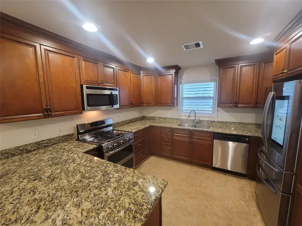 a kitchen with granite countertop a refrigerator stove top oven and sink