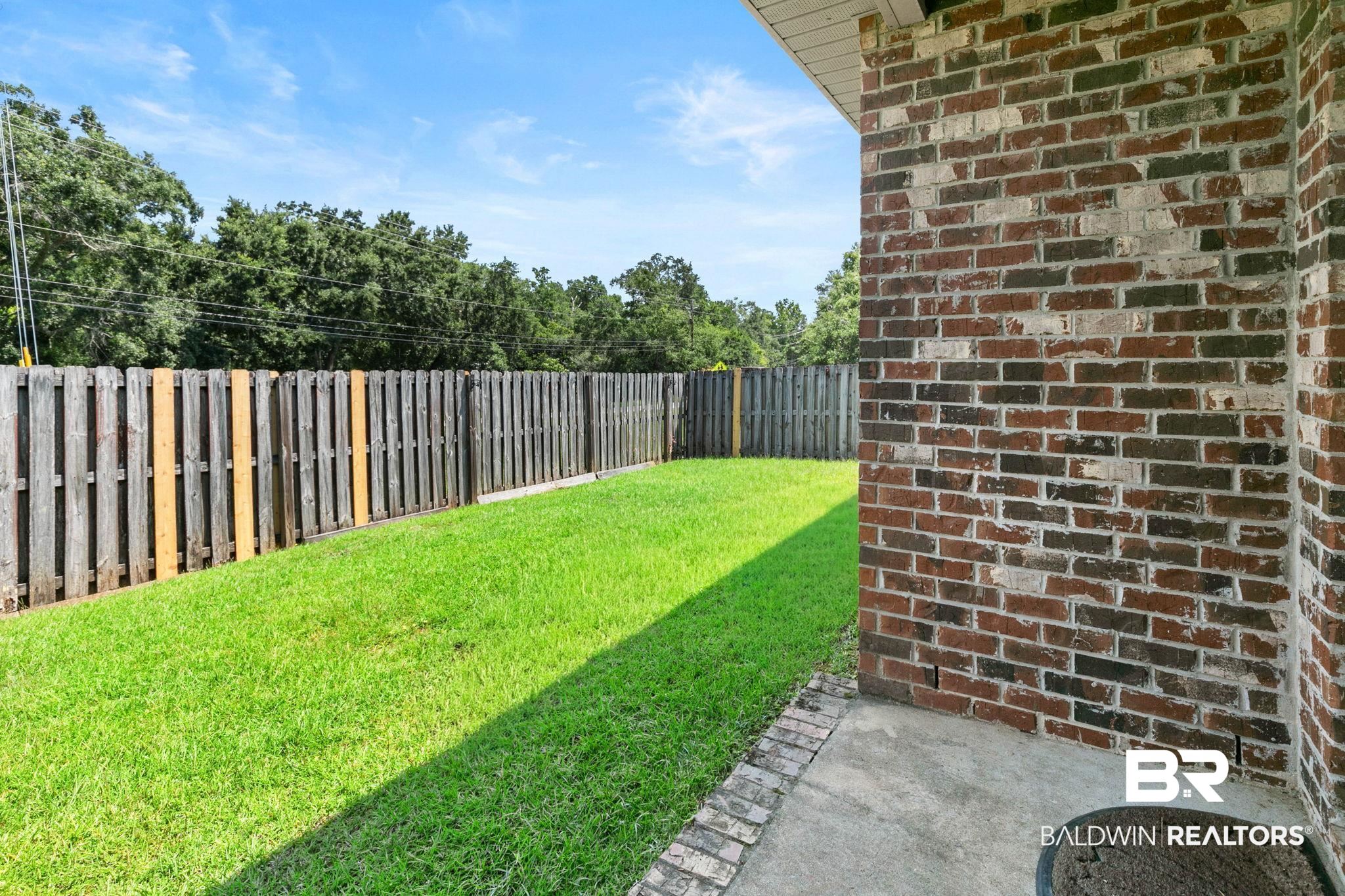 2216 Livingstone Court Mobile, AL 36695 - Photo 40 of 62 Expansive backyard featuring a manicured lawn, full privacy fencing, brick exterior wall, and concrete patio
