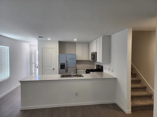 a view of kitchen with stainless steel appliances granite countertop refrigerator sink and stove