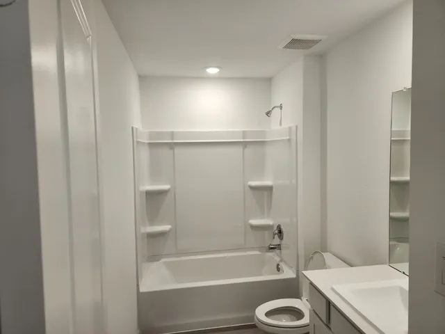 a bathroom with a granite countertop sink toilet and shower