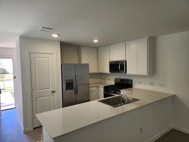 a kitchen with a refrigerator a sink a microwave and cabinets