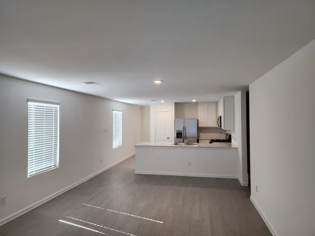 a large kitchen with a sink dishwasher a stove and a refrigerator with wooden floor