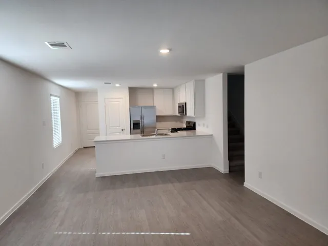 a large kitchen with kitchen island a sink wooden floor and stainless steel appliances