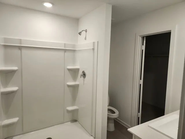 a bathroom with a granite countertop toilet and a shower