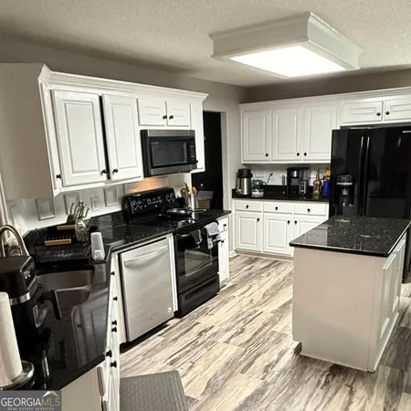 a kitchen with granite countertop a stove top oven a sink a counter space and cabinets