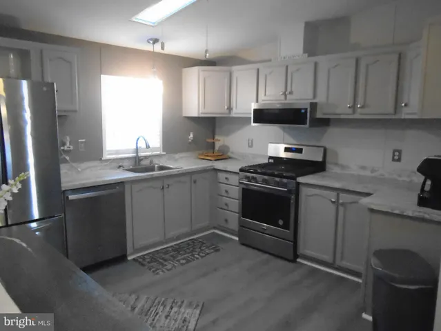 a kitchen with stainless steel appliances granite countertop a sink stove refrigerator and cabinets