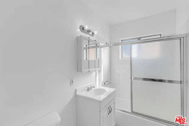 a bathroom with a shower sink vanity and a mirror