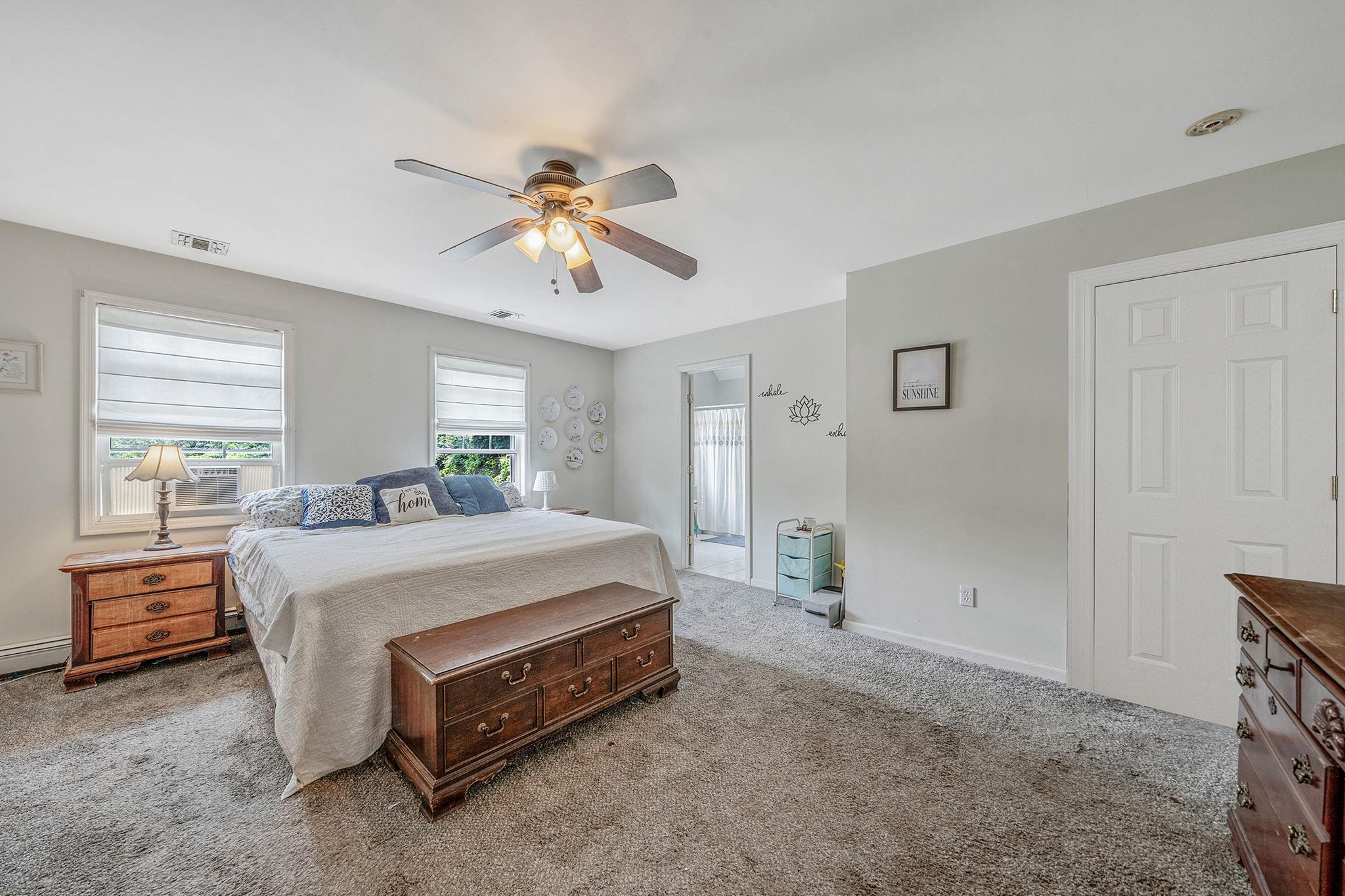 4 Ariel Court Rocky Point, NY 11778 - Photo 22 of 45 a spacious bedroom with a bed and a chandelier
