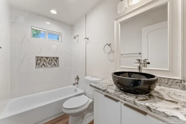 a bathroom with a granite countertop toilet sink and mirror