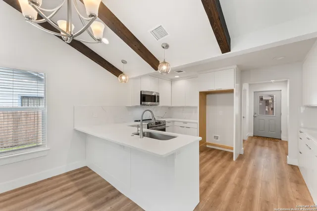 a kitchen with stainless steel appliances a large counter top a stove and a chandelier