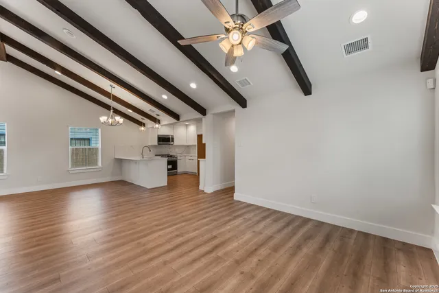 an empty room with wooden floor a ceiling fan and windows