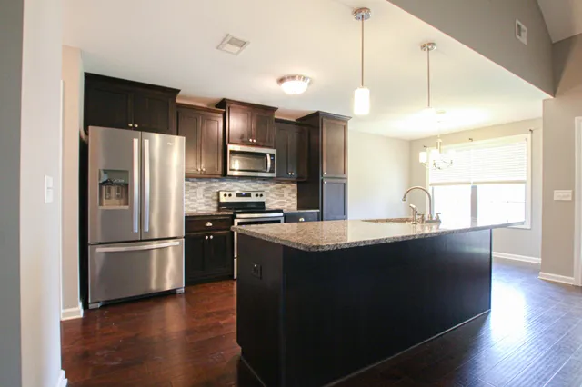 a kitchen with stainless steel appliances granite countertop a sink a stove and a refrigerator