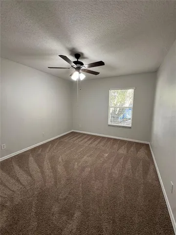 an empty room with windows and fan