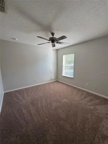 a view of a big room with windows and chandelier fan