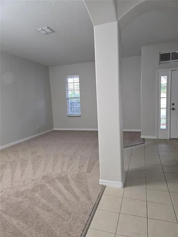 a view of an empty room with window and chandelier fan