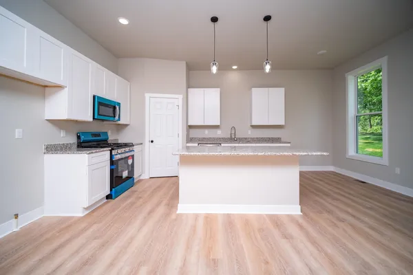 a large kitchen with granite countertop a large counter top a sink stainless steel appliances and cabinets