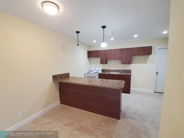 a view of kitchen with kitchen island stainless steel appliances a sink cabinets and a counter top space