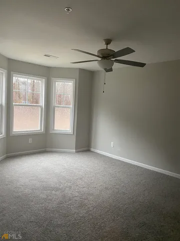 an empty room with windows and fan