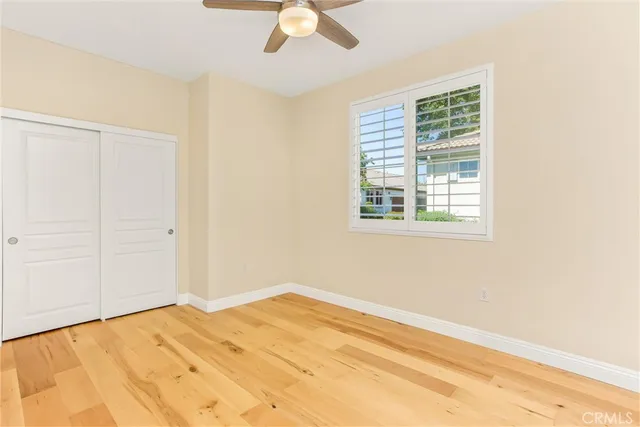 a view of a bedroom with wooden floor and a ceiling fan