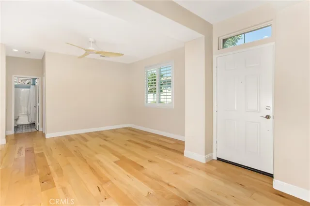a view of an empty room with wooden floor and a window