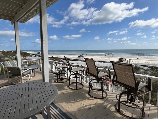 a balcony with wooden floor table and chairs