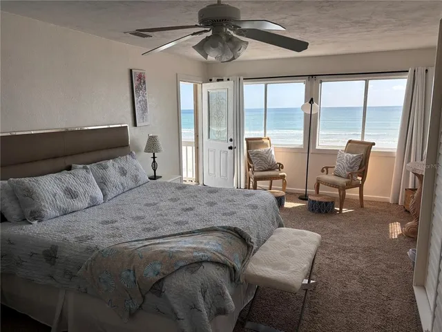 a spacious bedroom with a bed a large window with table and chairs