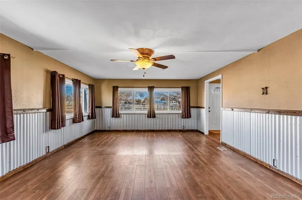 a view of an empty room with a window and wooden floor