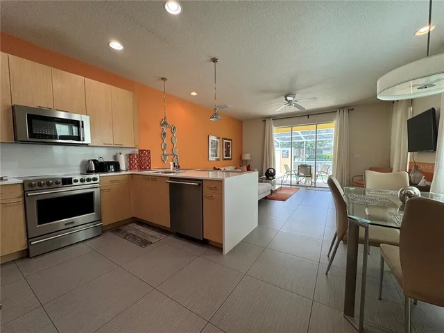 a kitchen with stainless steel appliances a stove a sink a microwave a dining table and chairs