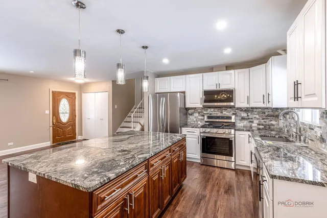 a kitchen with kitchen island granite countertop a stove and a sink