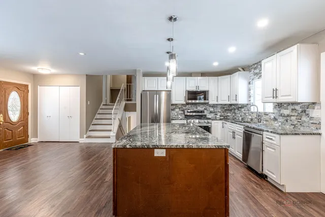 a large kitchen with stainless steel appliances granite countertop a stove a sink and a refrigerator