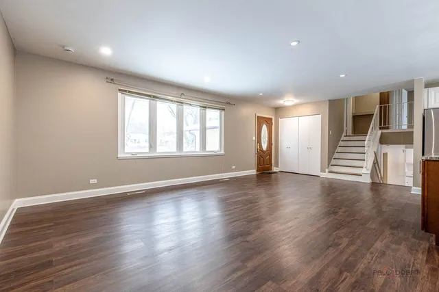 a view of an empty room with wooden floor and windows