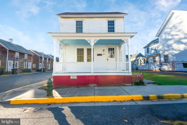 a view of pool with lawn chairs and large trees