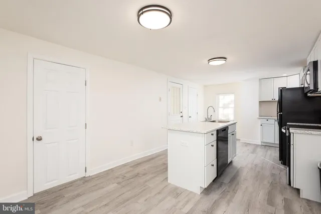 a kitchen with a sink cabinets stainless steel appliances and wooden floor