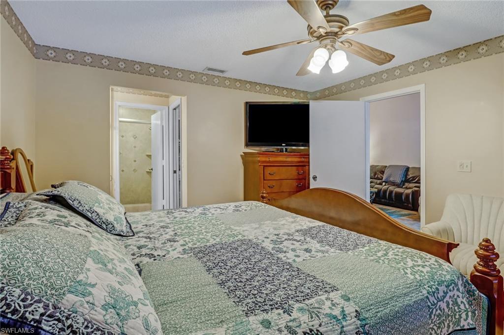 5675 Whitaker Road, Unit B202 Naples, FL 34112 - Photo 14 of 26 a bedroom with a bed and a flat screen tv