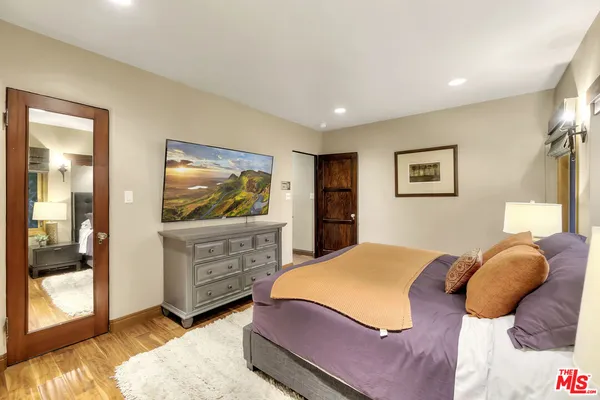 a kitchen with stainless steel appliances granite countertop a stove a sink dishwasher a refrigerator and white cabinets with wooden floor