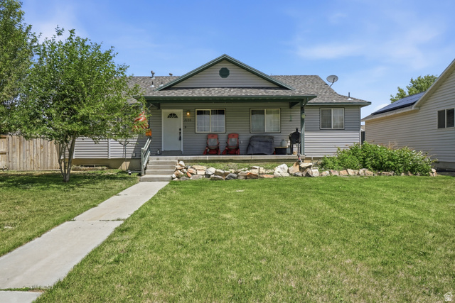 Single-story home featuring light gray siding with white trim, a covered front porch, and a contrasting dark gray roof