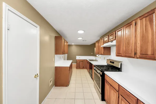 a kitchen view with stainless steel appliances a stove top oven a sink a refrigerator and white cabinets