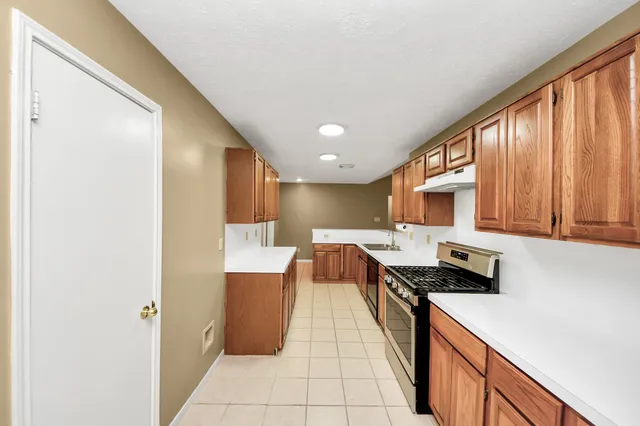 a kitchen view with stainless steel appliances a stove top oven a sink a refrigerator and white cabinets