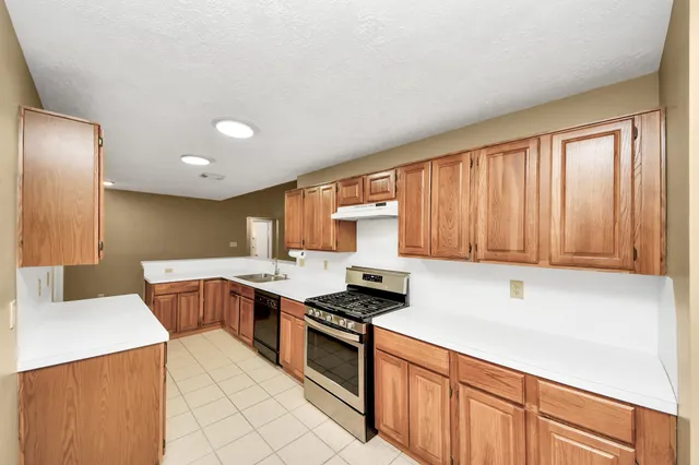 a kitchen with stainless steel appliances a sink a stove a refrigerator cabinets and a window