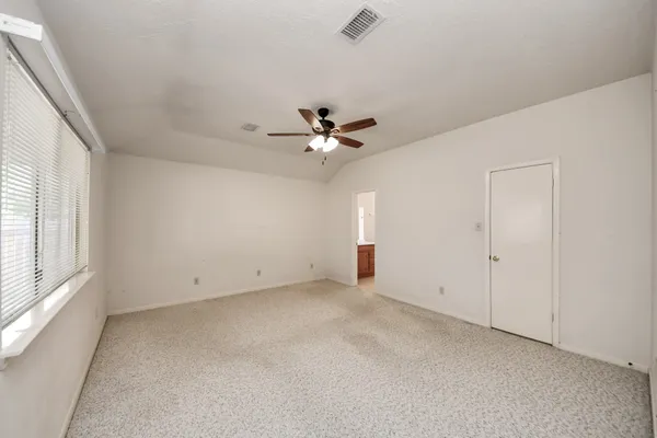 an empty room with a ceiling fan and window