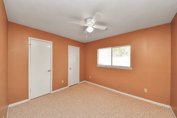 an empty room with a ceiling fan and a window