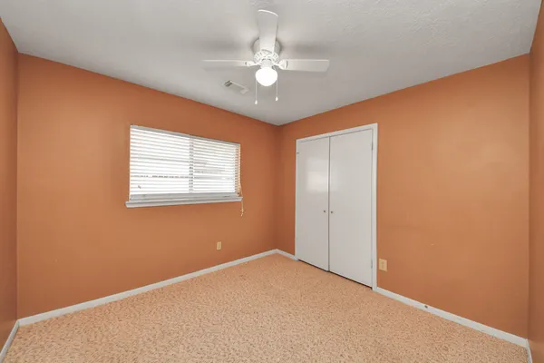 an empty room with a ceiling fan and a window