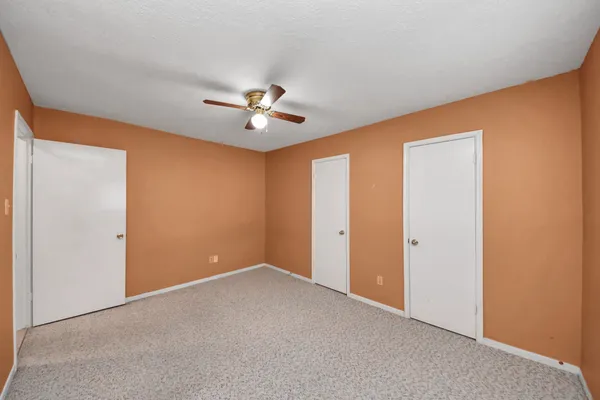 an empty room with a window and a chandelier fan