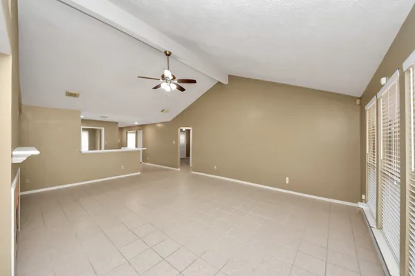 an empty room with ceiling fan and windows