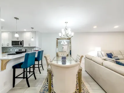 a dining room with furniture a chandelier and kitchen view