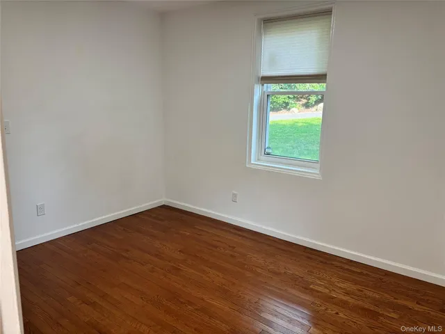 an empty room with wooden floor and a window