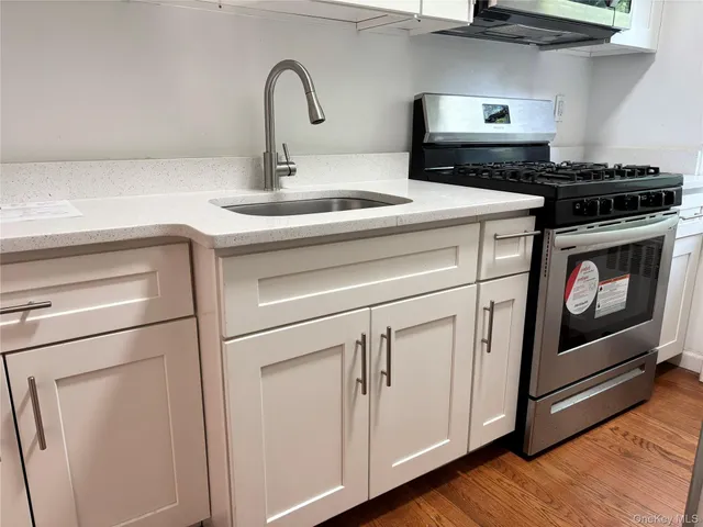 a kitchen with stainless steel appliances granite countertop white cabinets stove and wooden floor